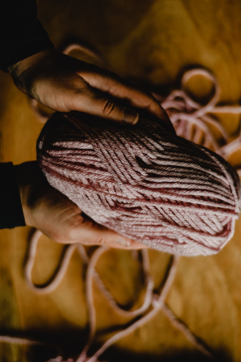 Hands holding a ball of naturally spun yarn in warm golden light